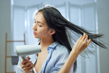A Beautiful Young Woman Use Hair Dryer