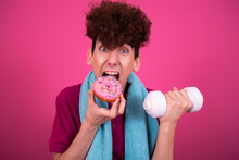 Sport And Retro Style. Young Attractive Guy On A Pink Background With Dumbbells And A Donut.