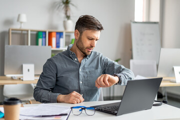 Poster - Business career and time management. Mature businessman using laptop and checking time, looking at watch