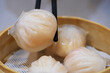 extreme close up of chopsticks picking Har gow (Xia jiao) from steamer. A traditional Cantonese snack served in dim sum