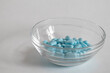 Pile of blue oblong pills in a pill box close-up, image shifted to the right