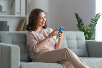 Poster - woman is using a phone sitting on a sofa