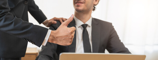 Close up view hand of boss encouraging employee by show thumb up after done good job