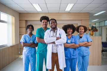 Young African american male doctor smiling while standing in a hospital  with a diverse group of staff in the background