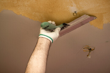 Wall Mural - Plasterer applies plaster to the ceiling at repair renovation work.