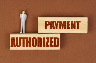 Poster - On wooden blocks with the inscription - Authorized Payment, there is a miniature figure of a businessman.