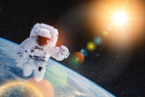 Fototapeta Kosmos - Astronaut in outer space with bright sun and lens flare. National Astronaut Day is an American commemorative day. Elements of this image furnished by NASA.