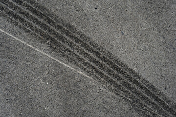 Asphalt texture with white line and tire marks. Smooth asphalt road. Tarmac dark grey grainy road background.Top view