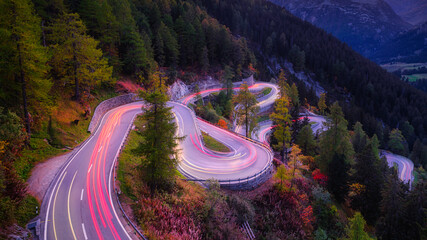 Canvas Print - Maloja pass, Switzerland. A road with many curves among the forest. A blur of car lights. Landscape in evening time.