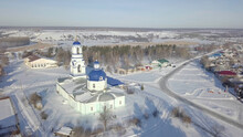Aerial View Of Local Orthodox Church In Russian Village With Blue Domes And Golden Crosses In Sunny Winter Day. Shot. Religion And Faith