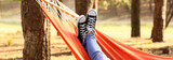 Fototapeta  - Legs of young woman relaxing in hammock outdoors
