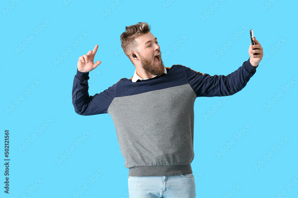 Cool dancing and singing young man on color background