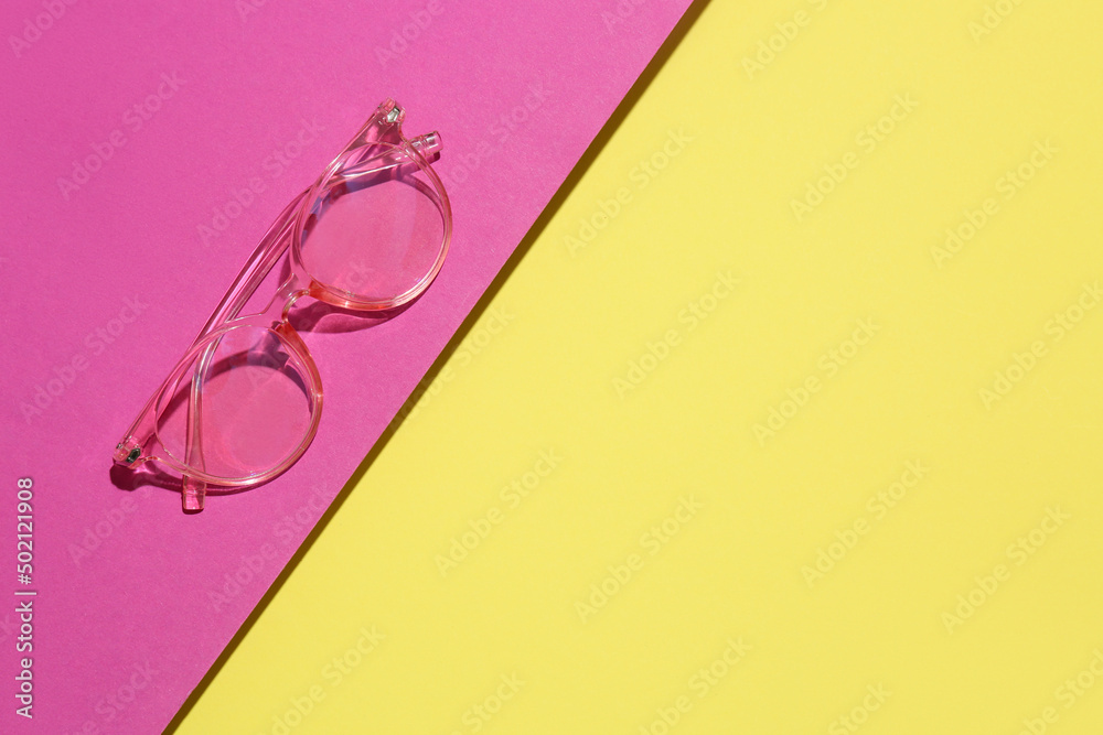 Pink eyeglasses on color background