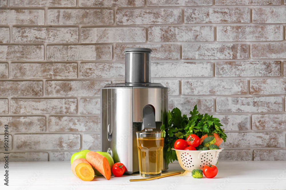 New modern juicer and glass of fresh juice on table