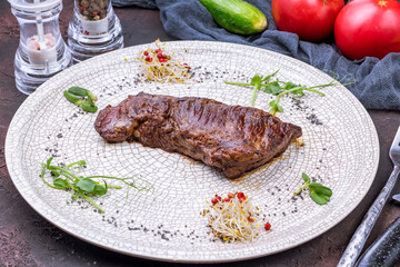 Sticker - roast beef Steak machete on grey plate on dark stone table side view