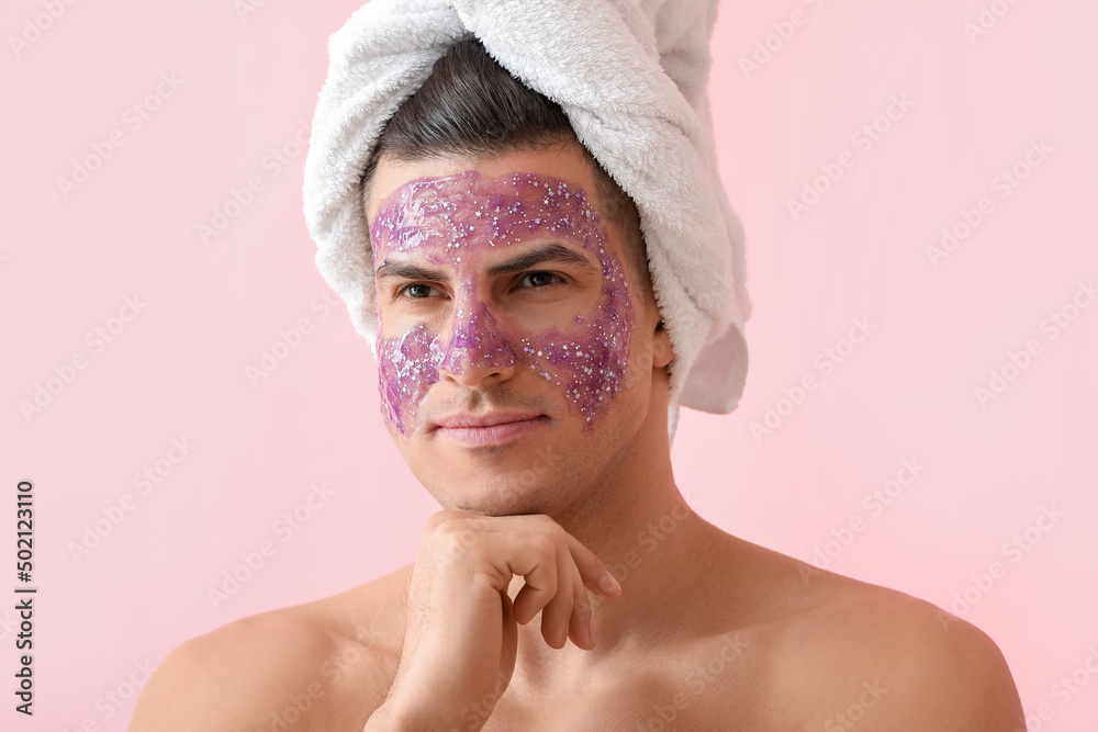 Handsome man with glitter mask and towel on pink background, closeup