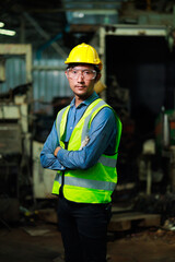 Wall Mural - Confident Asian man worker look at camera thumps up. Metal machine in heavy Industry Manufacturing. Asian male factory worker wearing safety hard hat helmet