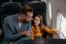 Cheerful Girl And Her Father Looking Out The Window In Airplane