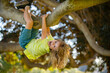 © Volodymyr - Young child blond boy climbing tree. Happy child playing in the garden climbing on the tree.