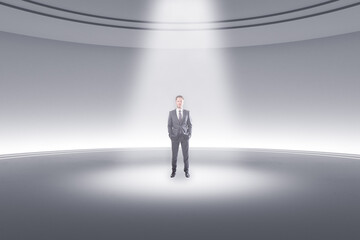 Thoughtful young businessman standing in abstract light round pedestal interior with spotlight.