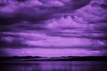 Wall Mural - purple sunset. sky with clouds over the sea. dramatic. mountains on the horizon. beautiful toned lan