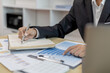 © Puwasit Inyavileart - Head of marketing is recording the company's financial growth statistics using graphs as a reference for reviewing and analyzing the results, Taking notes and analyzing data graphs in office.