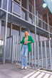 © unai - A blonde model woman in a green jacket in a beautiful building in the city. Summer vacation lifestyle