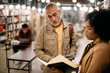 © Drazen - Mature student and his black female professor examining book in library.