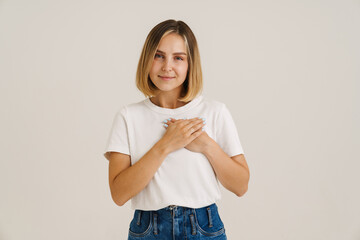 Young blonde woman smiling while holding hands on her chest