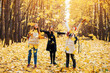 © EdNurg - a group of friends are having fun and toss yellow leaves in an autumn park. Fall season activities