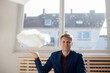 © Westend61 - Smiling businessman with levitating cloud network in office