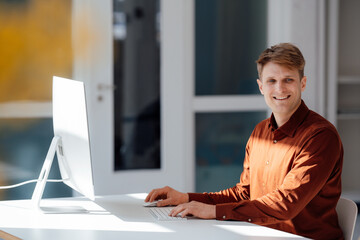 Smiling businessman sitting with computer at desk in office