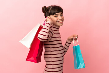 Wall Mural - Little caucasian girl isolated on pink background holding shopping bags and smiling