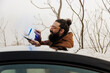 © Westend61 - Smiling bearded man touching navigation icon on smart phone standing by car