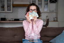 Young Woman Covering Mouth With Paper Currencies At Home