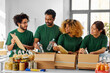 © Syda Productions - charity, donation and volunteering concept - international group of happy smiling volunteers packing food in boxes according to list on clipboard at distribution or refugee assistance center