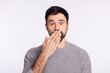 © Tetiana - Photo of young man cover lips hand oops fail tell secret worried nervous isolated over grey color background