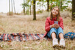 © Drobot Dean - White ginger girl using cellphone while sitting on blanket in forest