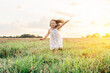 © Евгения Рубцова - Portrait of smiling girl playing, jumping and running on grass hay field paths of dry grass in the sunset. Waving hands. Forest on bright light background. Cloudy sunny sky. Haying time