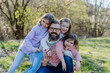 Father with his three little daughters looking at camera in spring nature together.