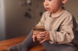 © Halfpoint - Close-up of child holding pot with plant growing from seeds at home, home gardening.