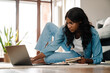 © Drobot Dean - Black young woman studying and using laptop at home