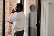 © Drobot Dean - Black bearded man drinking coffee while standing in doorway