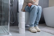 © zinkevych - A young woman sitting on a toilet bowl