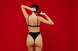 Back rear view young sexy brunette caucasian woman 20s with perfect fit body wear black underwear hold hair in ponytail isolated on plain red background studio portrait. People female beauty concept