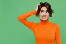 Young Puzzled Mistaken Pensive Sad Woman 20s Wear Casual Orange Turtleneck Look Aside Scratch Hold Head Isolated On Plain Pastel Light Green Color Background Studio Portrait. People Lifestyle Concept.