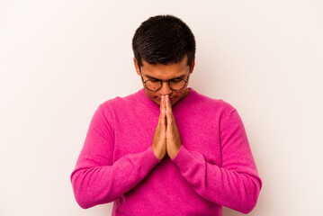 Young hispanic man isolated on white background praying, showing devotion, religious person looking for divine inspiration.