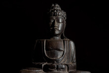 Sitting Buddha Statue In Lotus Position. It Is Made Of Palm Wood. Dark Image, Copy Space.