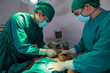 © sutthichai - Two Asian surgeons doctor working together on a surgery with male patient  in operation room.