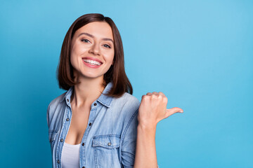 Wall Mural - photo of cheerful pretty girl direct thumb empty space novelty isolated on blue color background